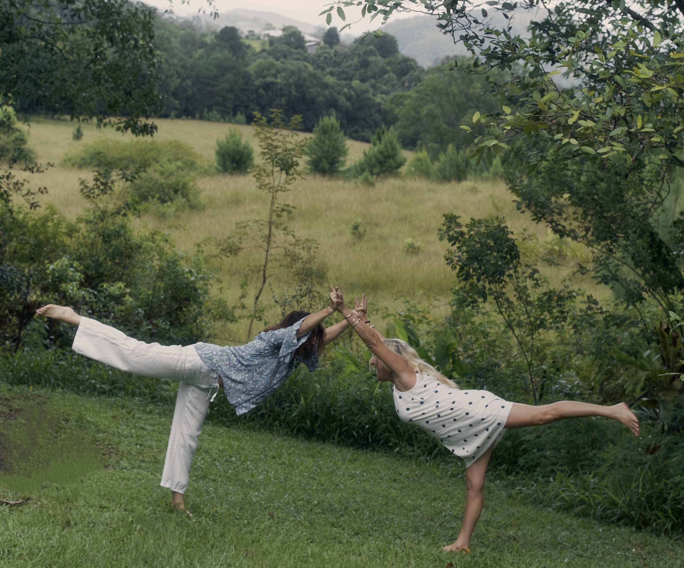 Mid shot of Bry and Lisa holding hands doing a Warrior Three pose