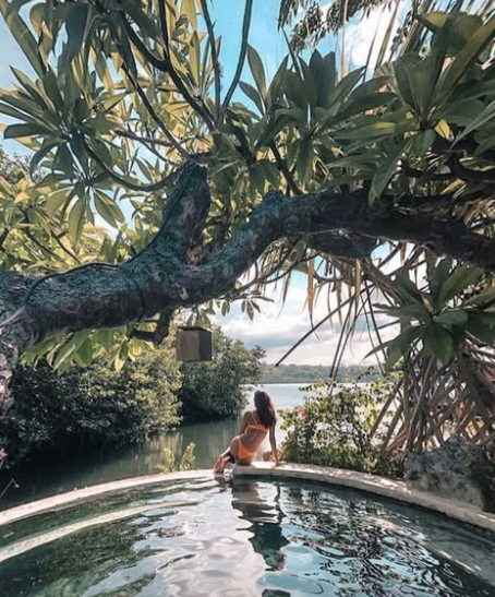woman at edge of pool under pandanas